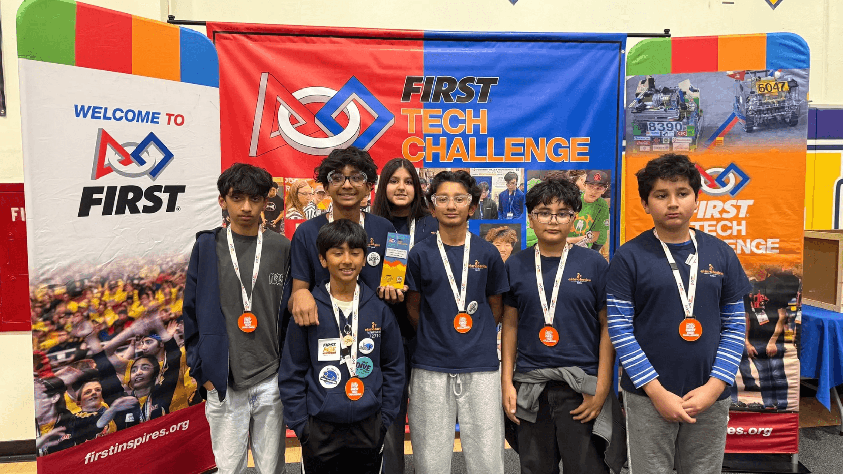 EIA Robotics students standing in front of FIRST Tech Challenge event banners.