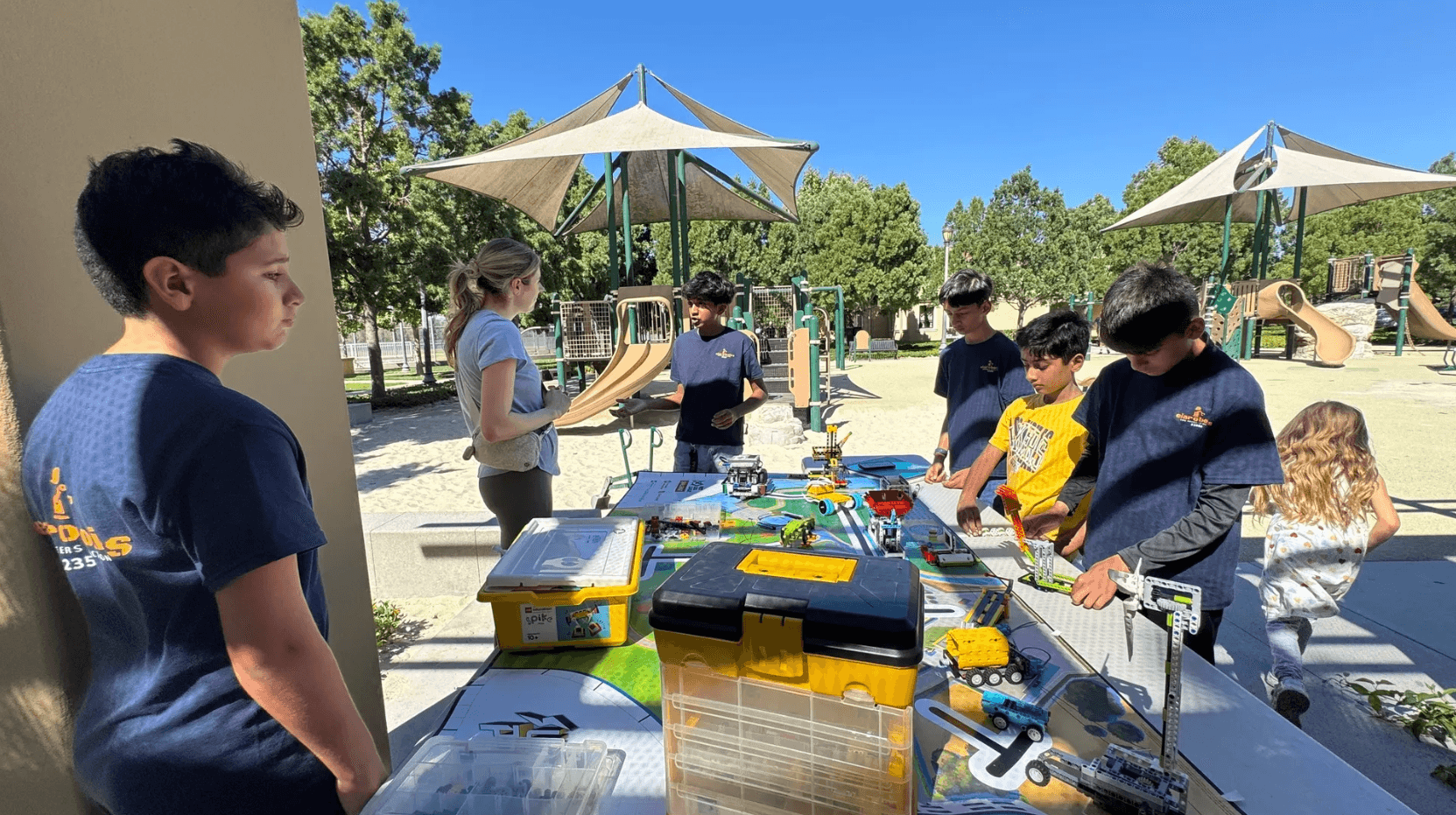 EIA Robotics students demonstrating LEGO robotics at an outdoor community table.